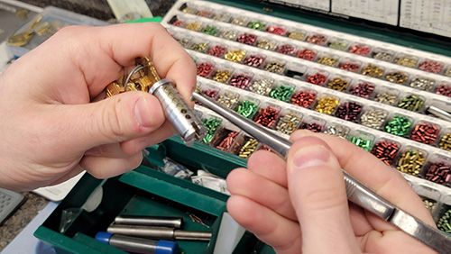 Locksmith repinning a brass lock cylinder on a workbench